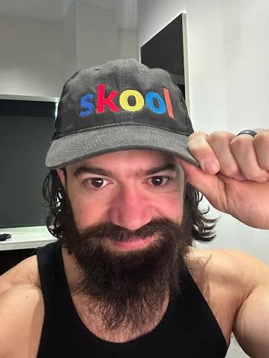 Alex Hormozi portant une casquette Skool, l'entrepreneur qui a rendu ses formations gratuites pour se financer au capital de sociétés